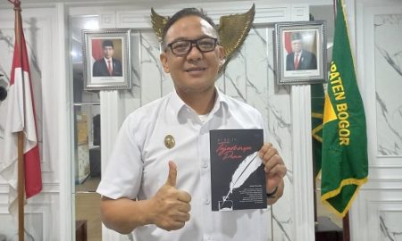Plt Bupati Bogor Iwan Setiawan memperlihatkan buku Di Balik Tajamnya Pena yang di-launching 20 jurnalis. (Arifin/Metropolitan
