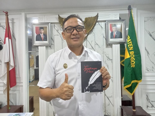 Plt Bupati Bogor Iwan Setiawan memperlihatkan buku Di Balik Tajamnya Pena yang di-launching 20 jurnalis. (Arifin/Metropolitan